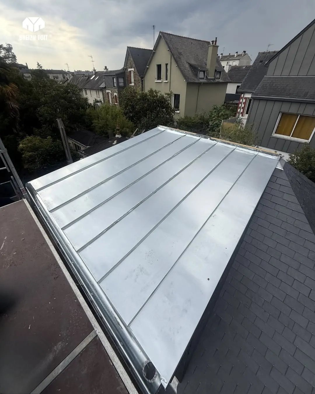 Lucarne rénovée en zinc sur une toiture en ardoises naturelles